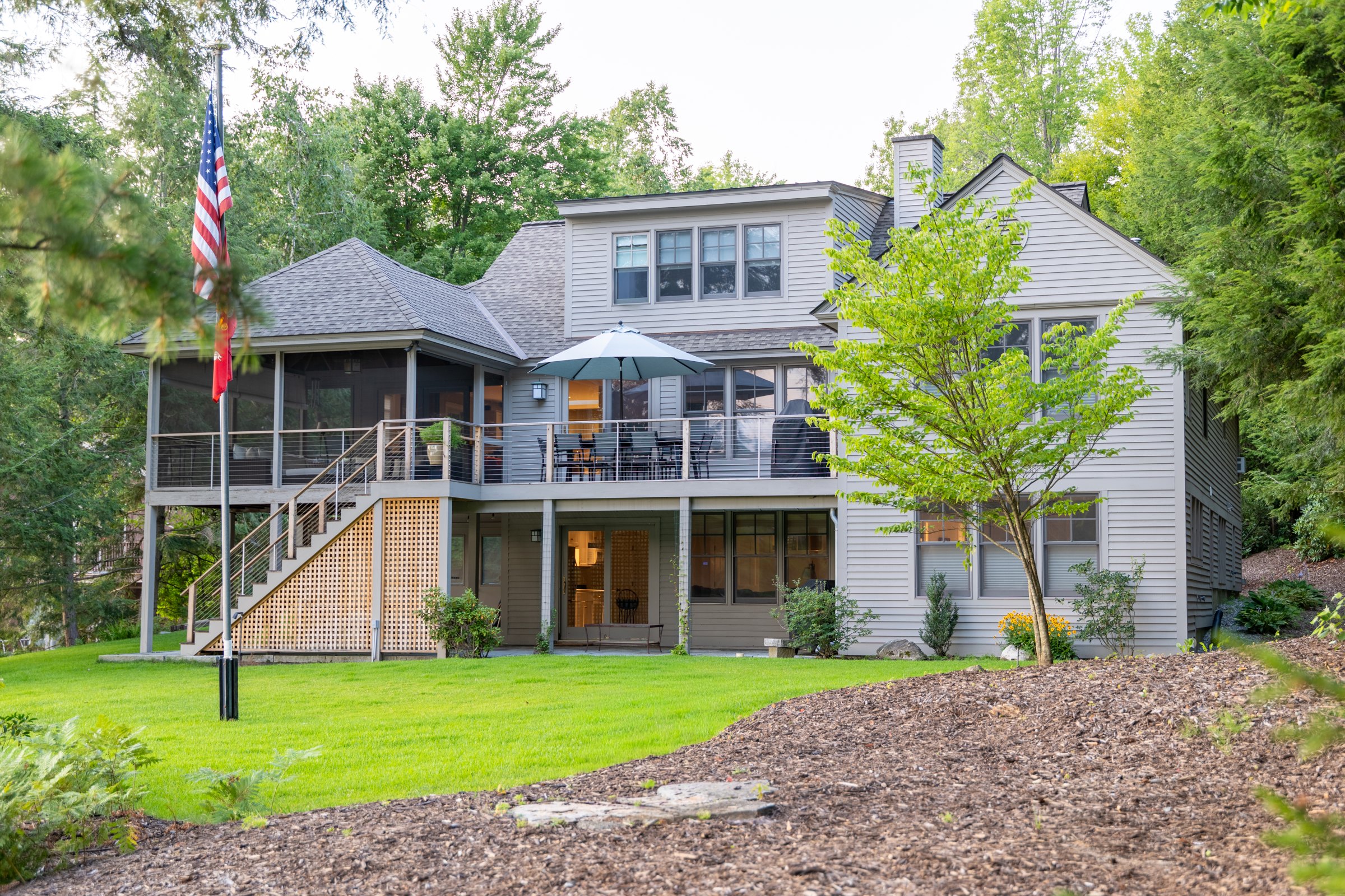 Woodland’s lake-facing exterior, deck, screened porch and lawn